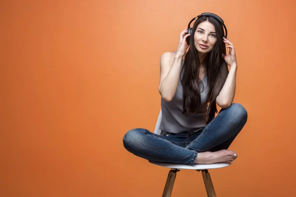 Mujer joven en auriculares escuchando música en la silla Fotos De Stock