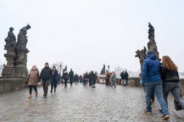 Prague, Çek Cumhuriyeti - Aralık 2018: Prag Kalesi ve Vltava Nehri manzaralı Charles Köprüsü üzerinde yürüyen turist 