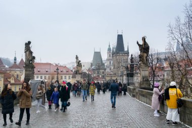 Prague, Çek Cumhuriyeti - Aralık 2018: Prag Kalesi ve Vltava Nehri manzaralı Charles Köprüsü üzerinde yürüyen turist 