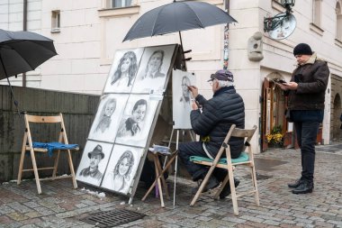 Prague, Çek Cumhuriyeti - Aralık 2018: bir portre fotoğraf Charles Köprüsü üzerinde gelen resmi bir sokak ressamın