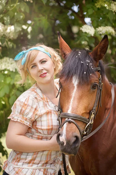 Neşeli, güzel sarışın kız bir ormandaki yaz güneşli havalarda nehrin bir atı ile yürüyor