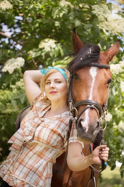 Neşeli, güzel sarışın kız bir ormandaki yaz güneşli havalarda nehrin bir atı ile yürüyor