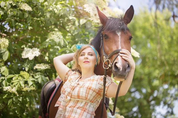 Neşeli, güzel sarışın kız bir ormandaki yaz güneşli havalarda nehrin bir atı ile yürüyor