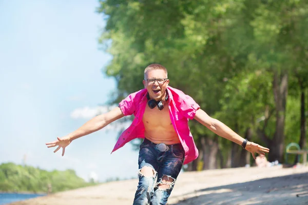 Parkta yürüyüş pembe gömlek giyen kulaklık ile şirin duygusal adam gözlük