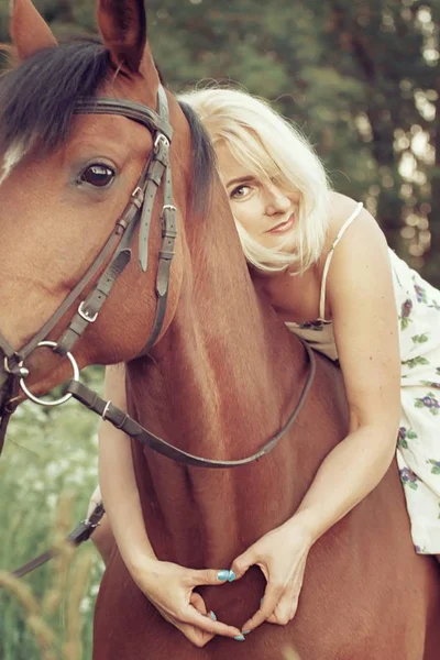 Ormandaki bir eyer olmadan atlı bir ışık hava elbiseli güzel seksi kadın binici sarışın yatıyor