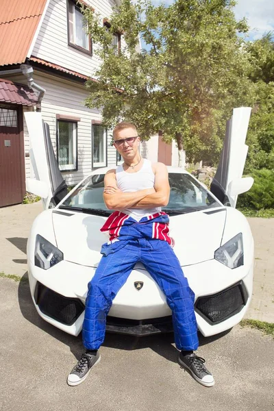 Gomel / Beyaz Rusya - 25 Haziran 2018: bir genç yakışıklı kaslı erkek yarış içinde kombenezone sürmek ve bir lamborghini aventador araba yaz güneşli havalarda pozlar