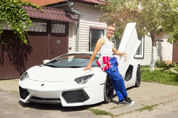 Gomel / Beyaz Rusya - 25 Haziran 2018: bir genç yakışıklı kaslı erkek yarış içinde kombenezone sürmek ve bir lamborghini aventador araba yaz güneşli havalarda pozlar