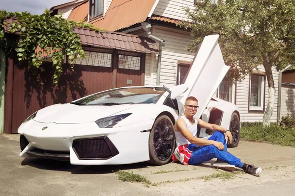Gomel / Beyaz Rusya - 25 Haziran 2018: bir genç yakışıklı kaslı erkek yarış içinde kombenezone sürmek ve bir lamborghini aventador araba yaz güneşli havalarda pozlar