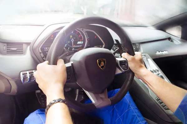 Gomel / Beyaz Rusya - 25 Haziran 2018: bir genç yakışıklı kaslı erkek yarış içinde kombenezone sürmek ve bir lamborghini aventador araba yaz güneşli havalarda pozlar