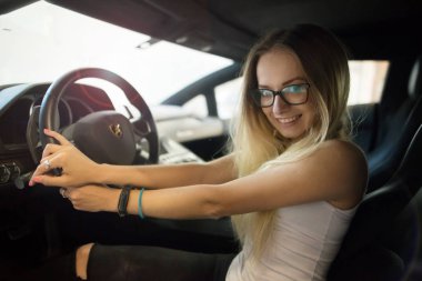 Gomel / Belarus - 1 Haziran 2018: gülümseyen, gözlüklü güzel bir kız yoldaki tozlu araba Lamborghini Aventador 'unda.