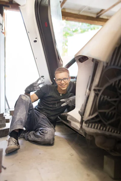 şirin neşeli karizmatik adam garajda pahalı bir araba siyah eldiven ve gözlük ile üzerinde çalışma