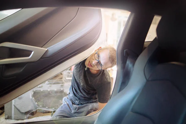 şirin neşeli karizmatik adam garajda pahalı bir araba siyah eldiven ve gözlük ile üzerinde çalışma