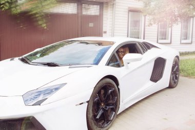 Gomel / Beyaz Rusya - 25 Haziran 2018: genç güzel sarışın kız gözlük racer ile yazın güneşli hava bir pahalı beyaz lamborghini avenue otomobilin direksiyonuna oturur
