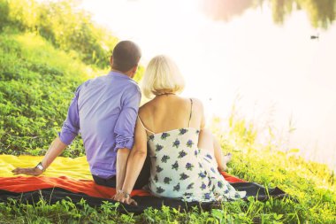 güzel bir çift zaman romantik nehir kıyısında sıcak yaz havalarda gün batımında harcıyor. bir erkek ve bir kadın kucaklama. aşk