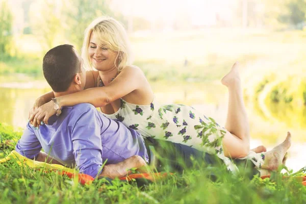 güzel bir çift zaman romantik nehir kıyısında sıcak yaz havalarda gün batımında harcıyor. bir erkek ve bir kadın kucaklama. aşk