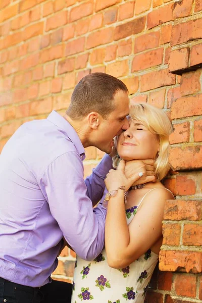 爱的女人金发女郎和一个男人在红色彩绘 Kerber 墙浪漫拥抱接吻 — 图库照片