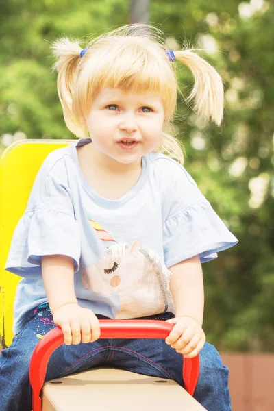 夏の晴れた日の遊び場で遊んで つの尾を持つ陽気な金髪少女 — ストック写真