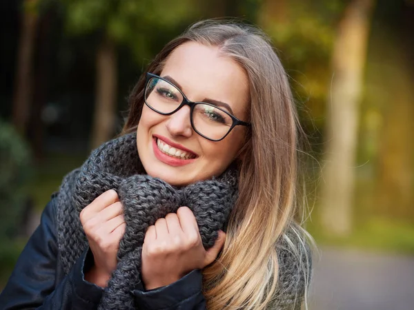 bir güzel şık genç sarışın kız siyah gözlük deri ceket ve örme eşarp makyajlı portresi Don yukarıya sonbahar soğuk parkta gülümsüyor