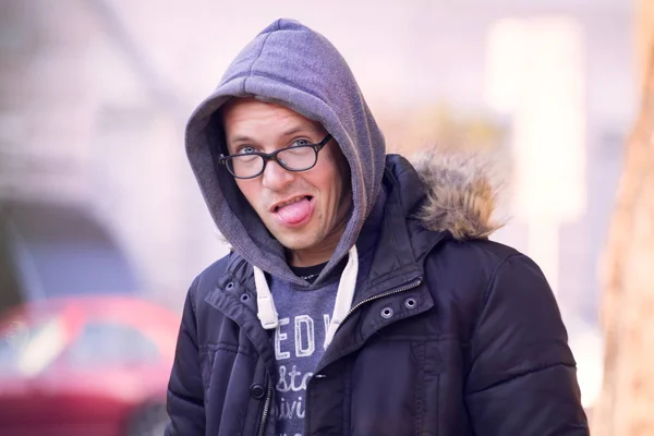 handsome cheerful short-cut man in black glasses in a black jacket walks through the autumn streets of the city