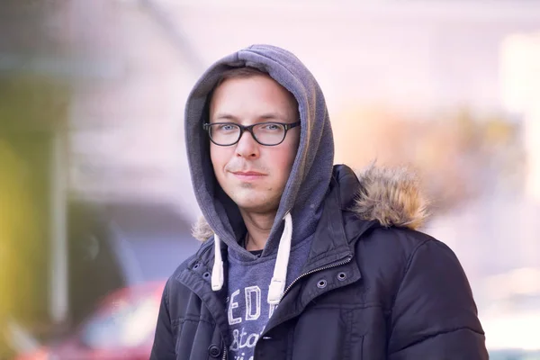 handsome cheerful short-cut man in black glasses in a black jacket walks through the autumn streets of the city