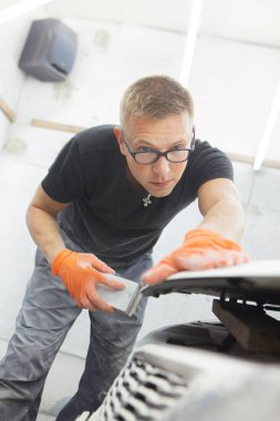 turuncu eldiven ile siyah gözlüklü şirin adam mahalle için arabanın sonraki resim şeklinde görüntüler. adam - bir ev bir araba garajda çalıştığı ressam 