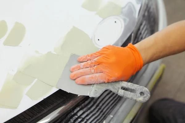 Zemin ile turuncu eldiven erkek elinde shpakalom araba kukuleta garajda ile