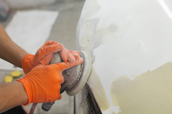 男子的手戴橙色手套 用气动抛光机擦亮车库里的汽车引擎盖 — 图库照片