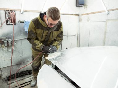 şirin neşeli adam gözlüklü yeşil elbiseli bir arabanın kaputuna bir pnömatik Parlatma makine ile parlatır.