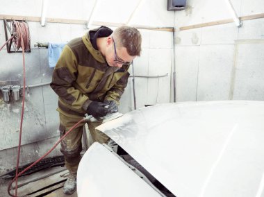 şirin neşeli adam gözlüklü yeşil elbiseli bir arabanın kaputuna bir pnömatik Parlatma makine ile parlatır.