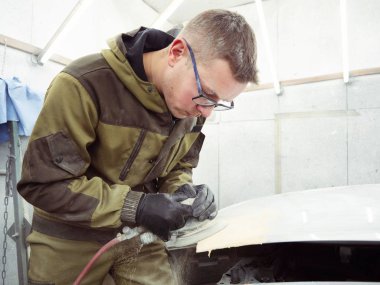 şirin neşeli adam gözlüklü yeşil elbiseli bir arabanın kaputuna bir pnömatik Parlatma makine ile parlatır.