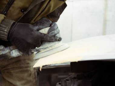 men's hands in black gloves polish the hood of the car with a pneumatic polisher in the garage clipart