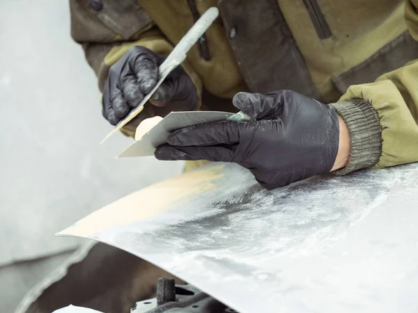 cute guy with glasses putty a car hood section of a garage in black gloves