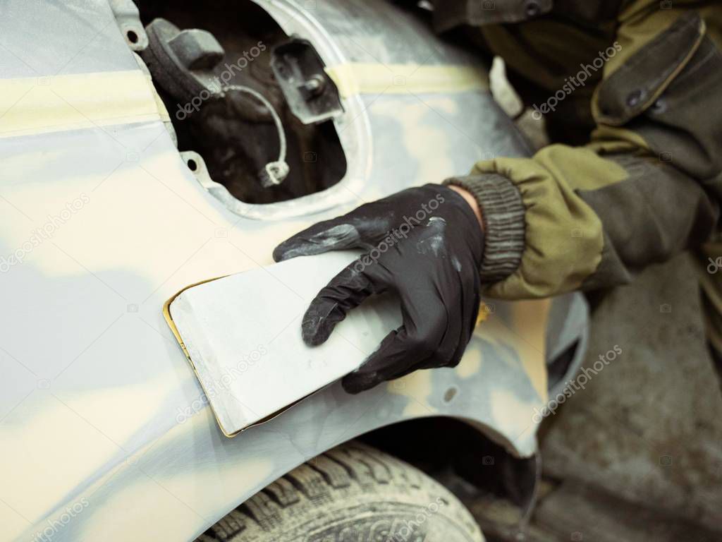 Men's black-gloved hands take the form of a hood for later driving. man works in the garage