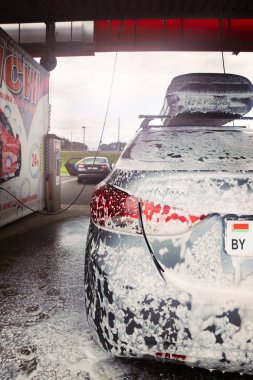 Gomel, Belarus - 4 Ağustos 2019: Gözlüklü sakallı bir adam gümüş renkli araba yıkar Hyundai Elantra GLS