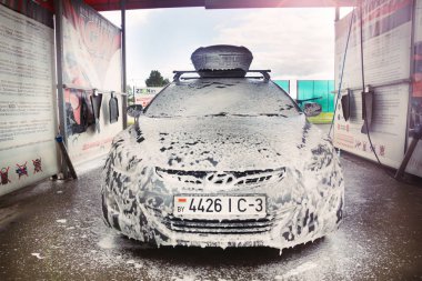 Gomel, Belarus - 4 Ağustos 2019: Gözlüklü sakallı bir adam gümüş renkli araba yıkar Hyundai Elantra GLS