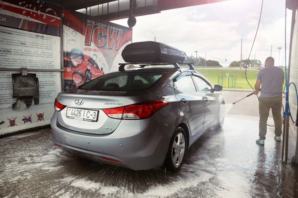 Gomel, Belarus - 4 Ağustos 2019: Gözlüklü sakallı bir adam gümüş renkli araba yıkar Hyundai Elantra GLS