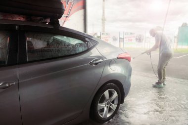 Gomel, Belarus - 4 Ağustos 2019: Gözlüklü sakallı bir adam gümüş renkli araba yıkar Hyundai Elantra GLS