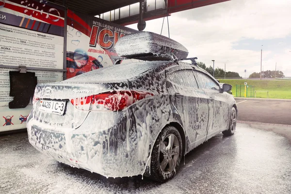 Gomel, Belarus - 4 Ağustos 2019: Gözlüklü sakallı bir adam gümüş renkli araba yıkar Hyundai Elantra GLS
