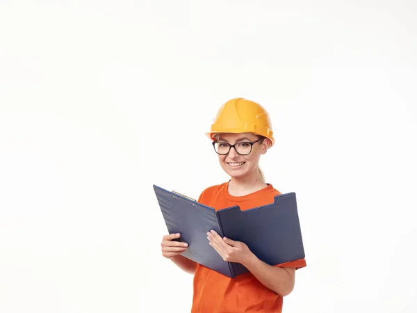 白い背景に青いフォルダを持つ黄色のヘルメットの美しいフォアマンの女の子 — ストック写真