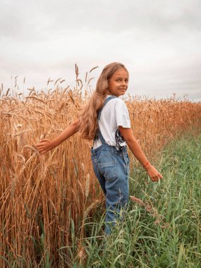 Bir buket papatyayla tarlada uzun saçlı bir kız.