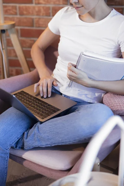 Online education. The girl is sitting in a chair with a laptop and notebook engaged with the teacher online. Online lessons. Online language lessons.