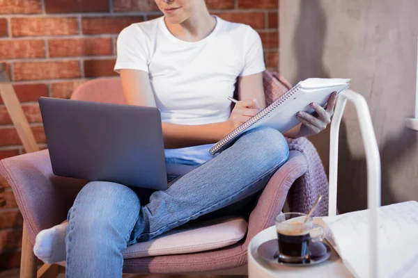 Online education. The girl is sitting in a chair with a laptop and notebook engaged with the teacher online. Online lessons. Online language lessons.