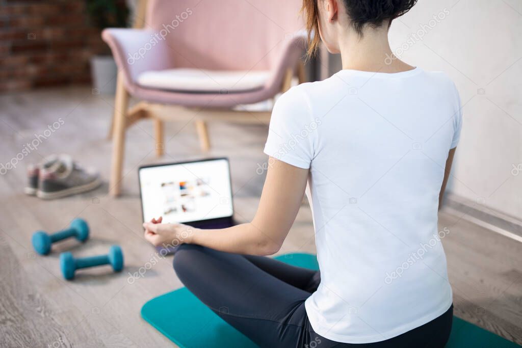 Young sporty slim woman has internet video online fitness training instructor modern laptop screen. Healthy lifestyle concept, online fitness and sport lessons. Stretching online.