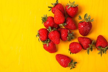 Sarı arka plan üzerinde olgunlaşmış taze çilek. Meyve yakın çekim