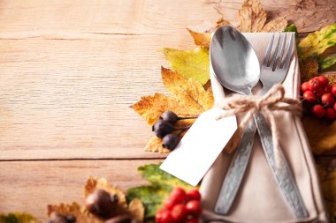 Şükran Günü güz yeri çatal bıçak takımı ve renkli sonbahar yapraklarıyla donatılmış.