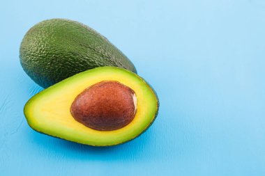 Eski ahşap masada avokado. Ahşap kasede yarısı. Meyve sağlıklı gıda konsepti.