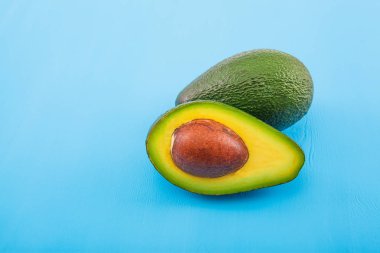 Eski ahşap masada avokado. Ahşap kasede yarısı. Meyve sağlıklı gıda konsepti.