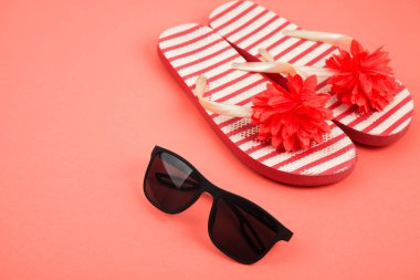 Mercan arka planda parmak arası terlik ve güneş gözlüğü