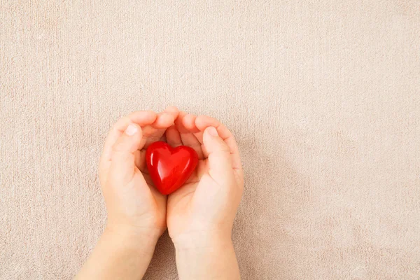 Mãos de criança segurando coração vermelho — Fotografia de Stock