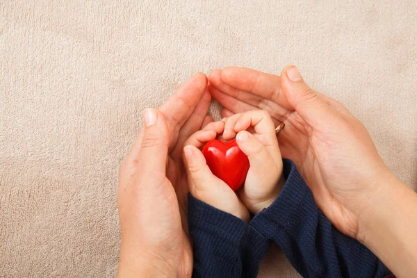 Dospělé a dětské ruce červené srdce — Stock fotografie